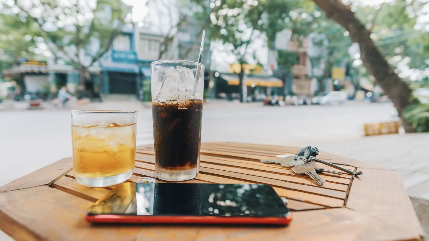 Car keys, a smartphone and two iced drinks left on a wooden cafe table