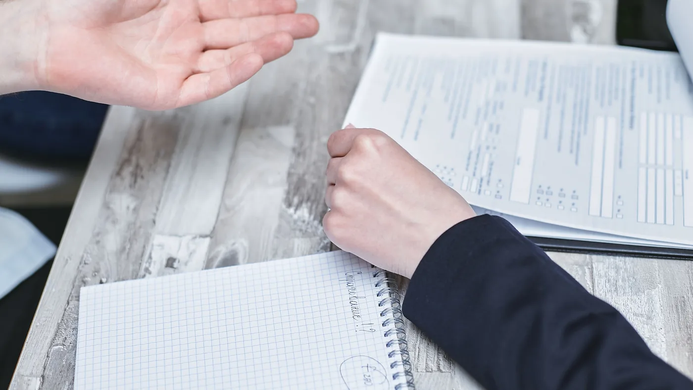 Two people at a desk going over paperwork, one hand gesturing toward a printed form