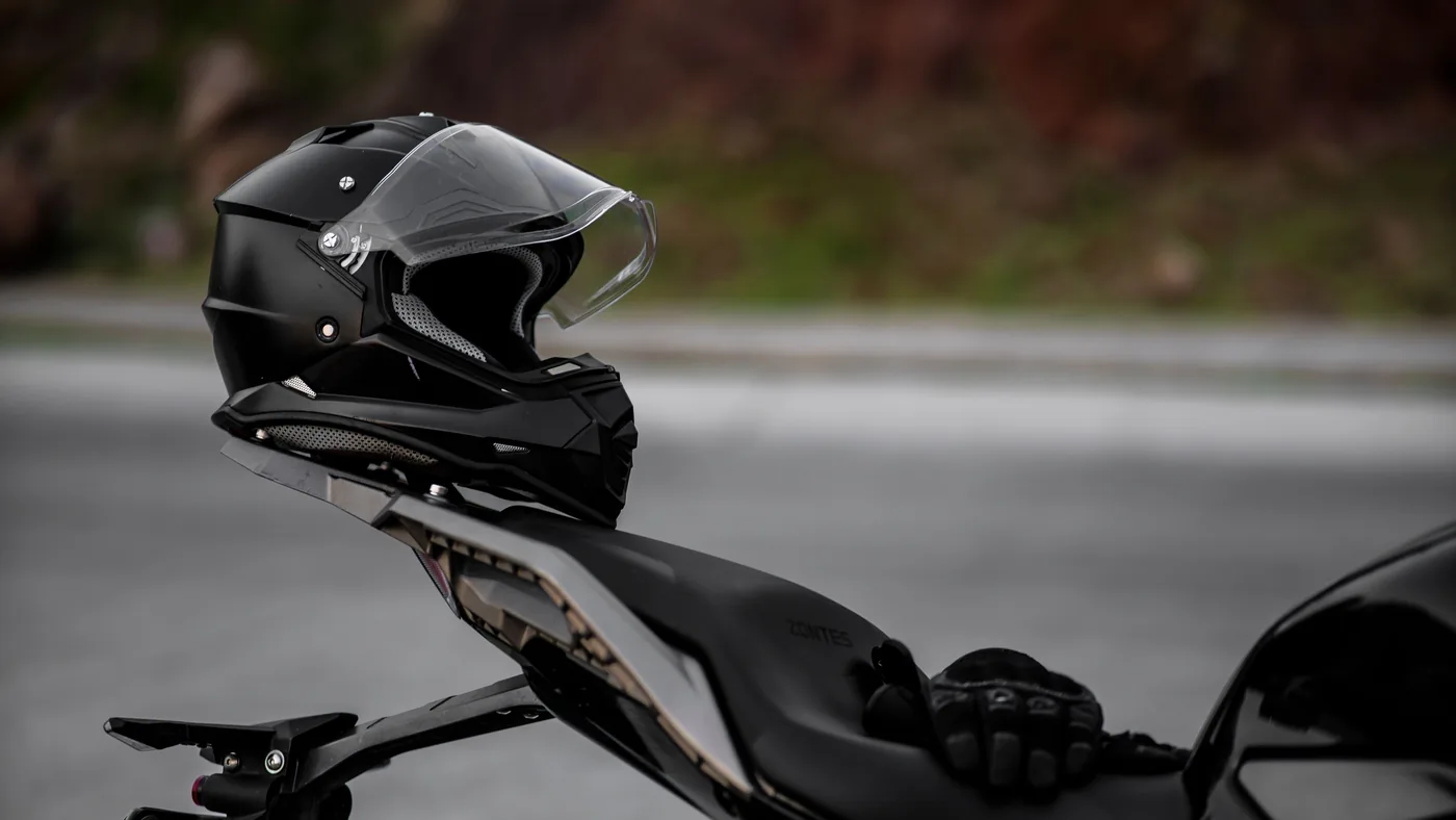 Black motorcycle helmet and riding gloves resting on the seat of a parked motorcycle
