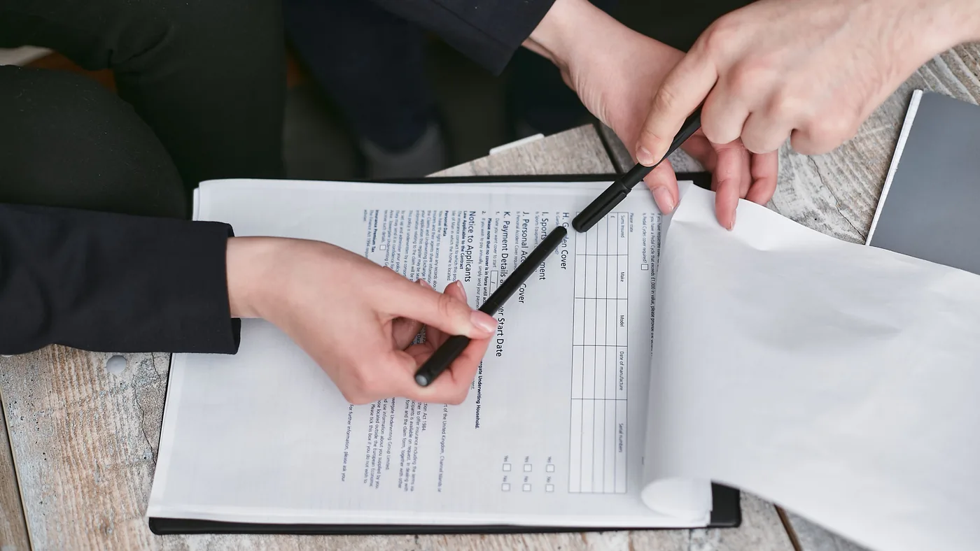Two people at a table going over a printed document, one holding a pen
