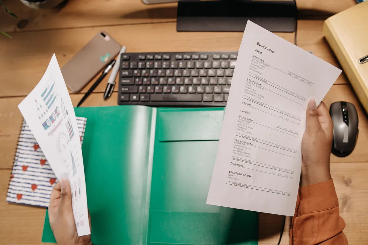 Person reviewing a balance sheet and financial report at a desk